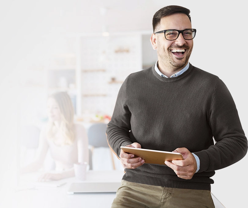 Homem de culos sorrindo com tablet nas mos.